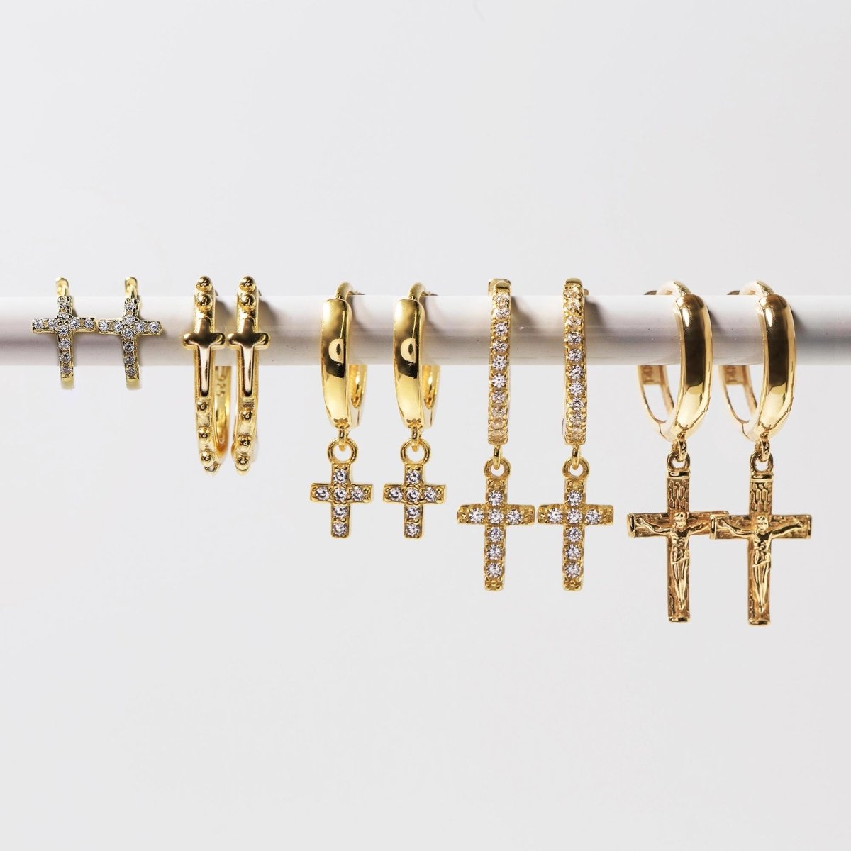 Gold vermeil cross pavé huggie hoops shown in a lineup of cross earring styles, on a white background