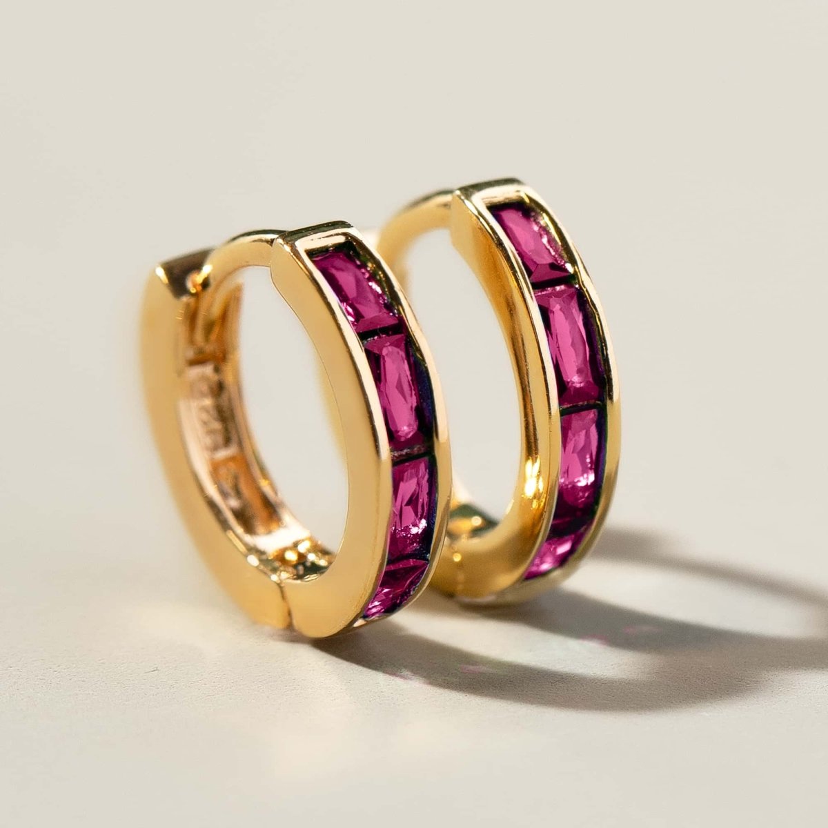 Gold vermeil huggie hoops set with red baguette stones, angled close-up detail