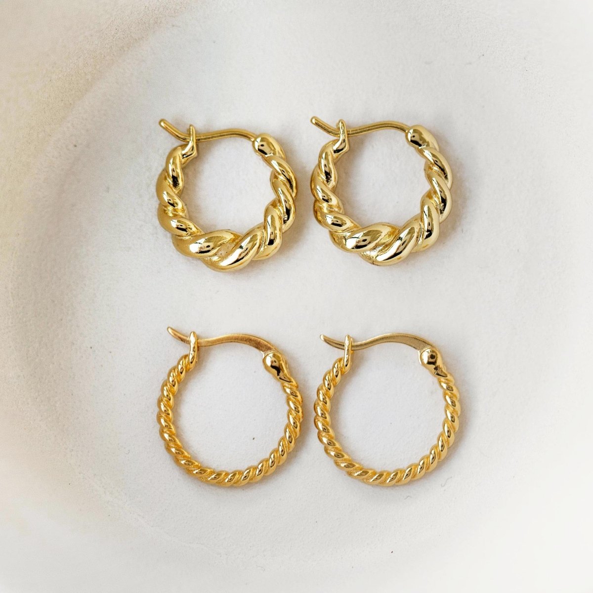 Gold vermeil twisted rope huggie hoops in two sizes, shown loose on a white surface