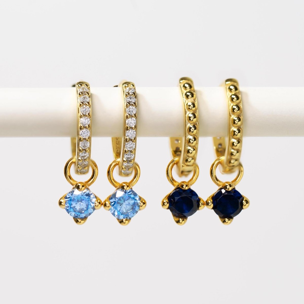 Gold vermeil pavé and beaded huggie hoops with round light-blue and dark-blue charms, on a white background