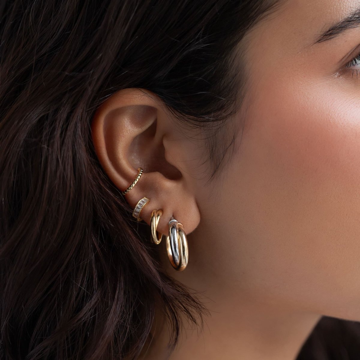 Gold vermeil baguette huggie hoop with clear stones, styled in a model's ear stack