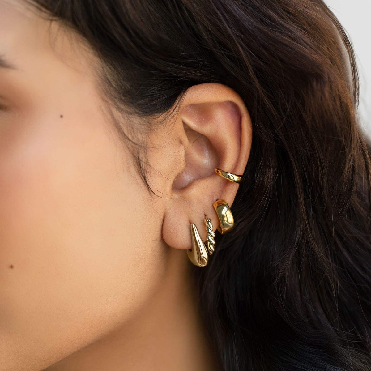 Gold vermeil tapered huggie hoop styled in an ear stack on a model's lobe