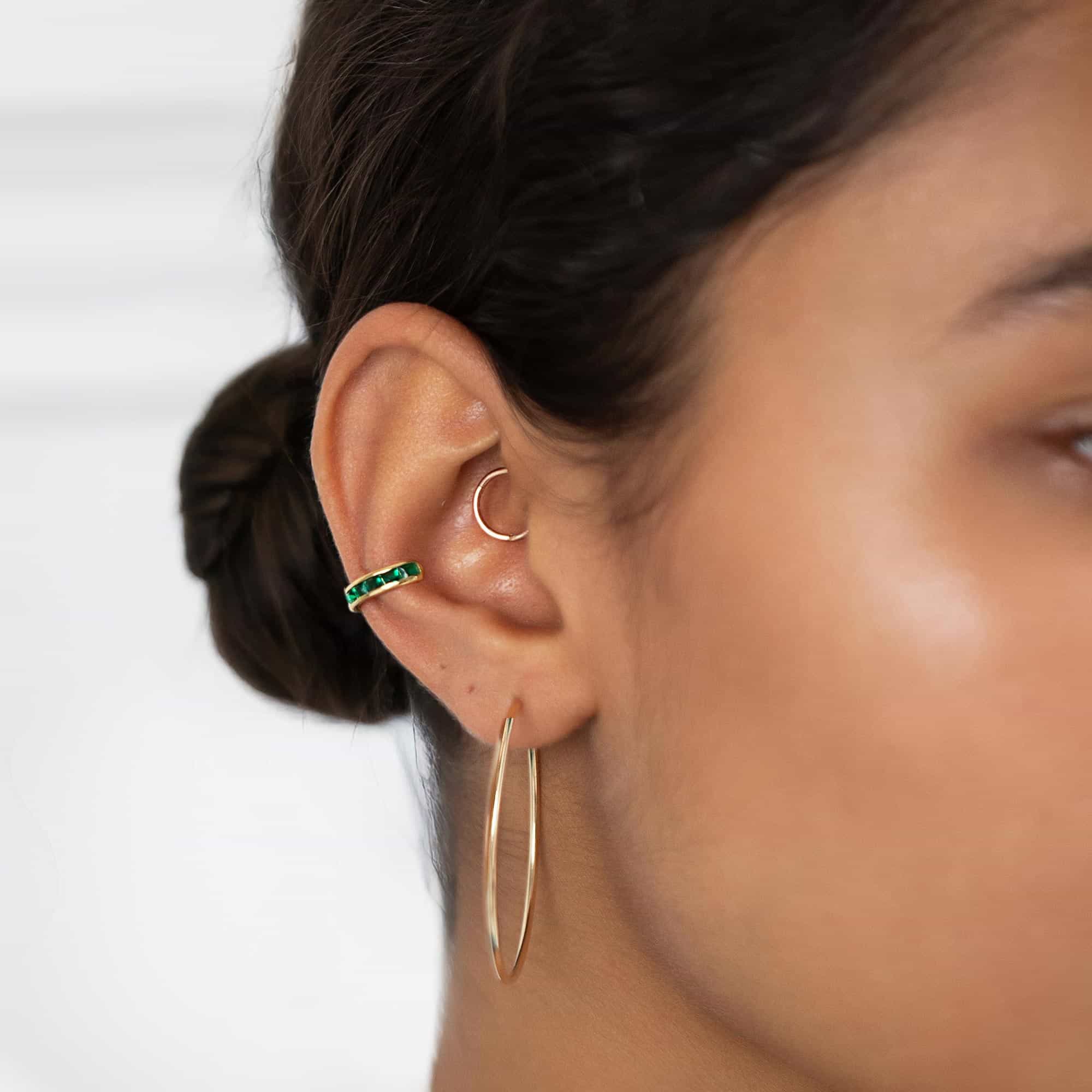 Gold vermeil princess cut emerald ear cuff with green stones, shown on a model's ear