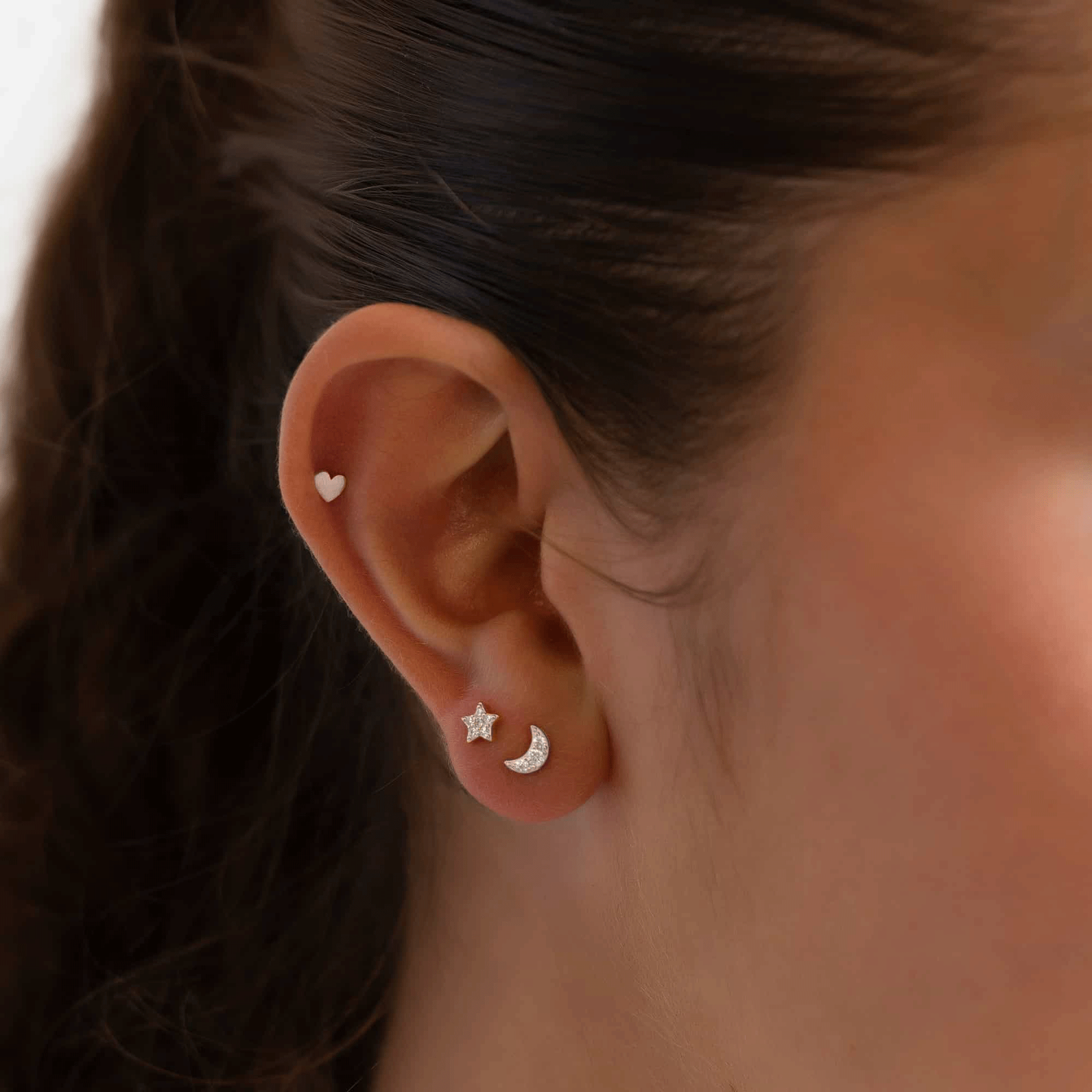 Sterling silver pavé star and moon flat back studs shown in a model's lobe stack