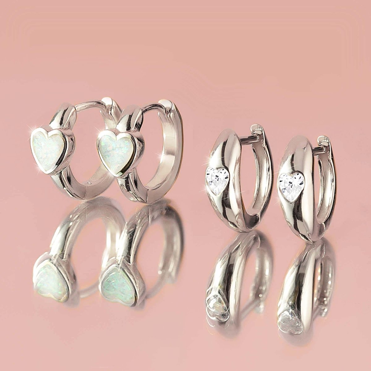 Sterling silver opal heart huggie hoops beside clear heart-stone huggies, close-up detail