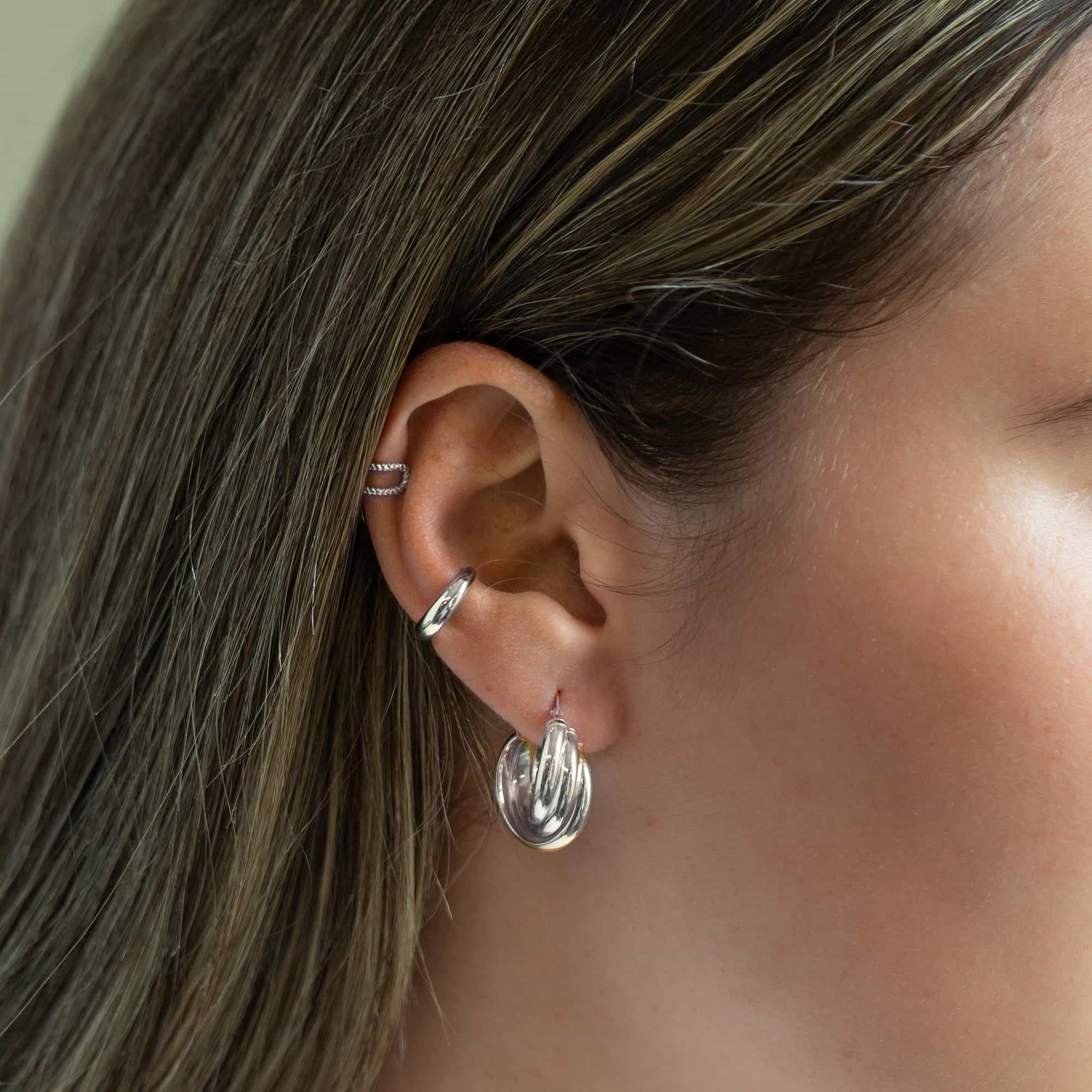 Silver twisted hoop with rope ear cuffs styled along a model's ear