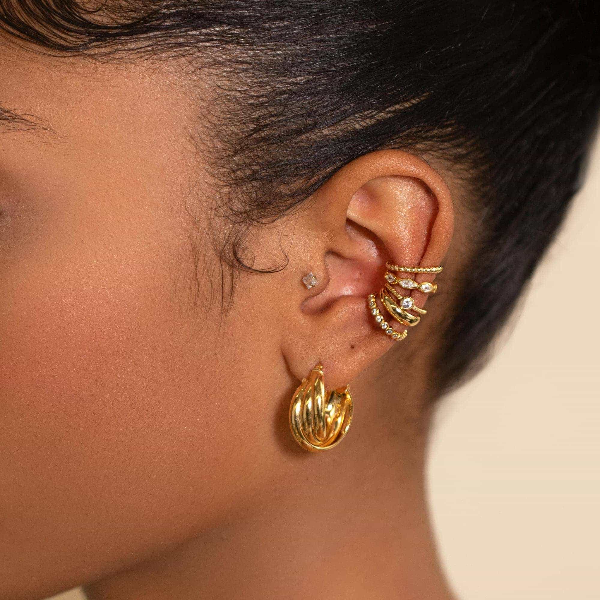 Gold twisted hoop with stud and clear-stone ear cuffs styled along a model's ear