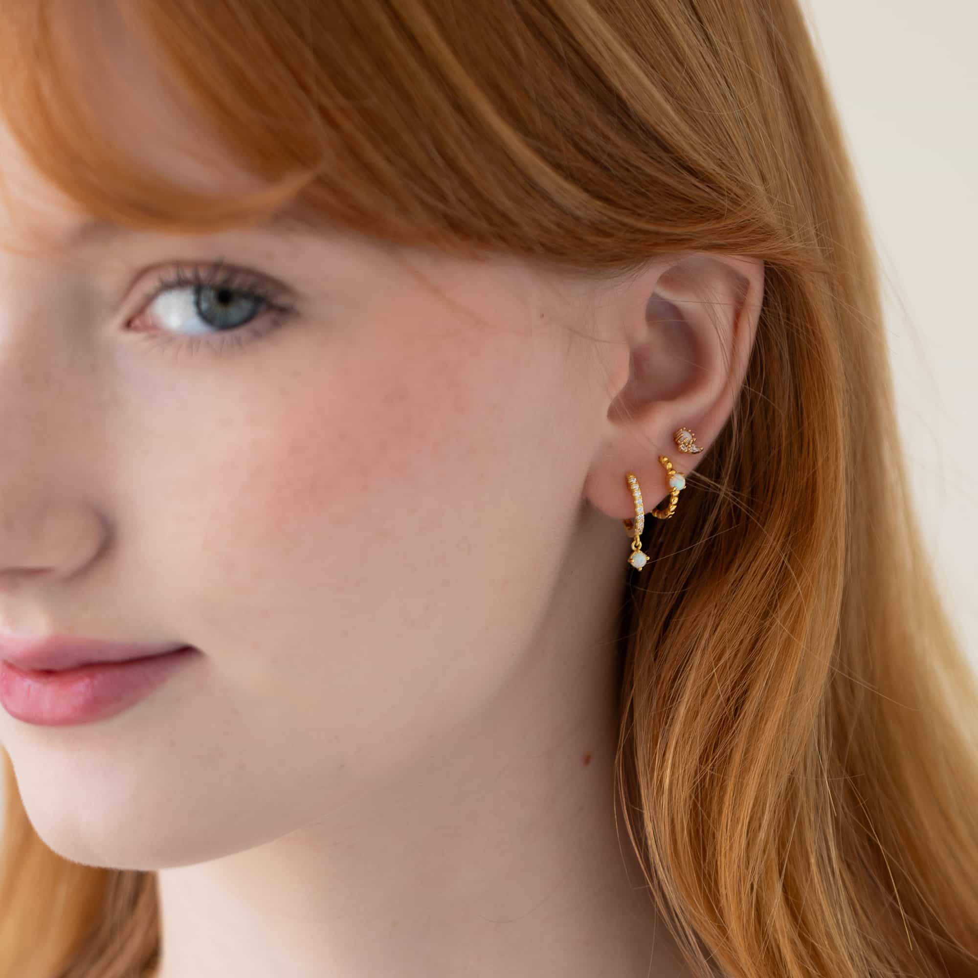 Side profile of woman featuring Gold Vermeil Gemstone Bead Huggies Opal, hoop, and stud.