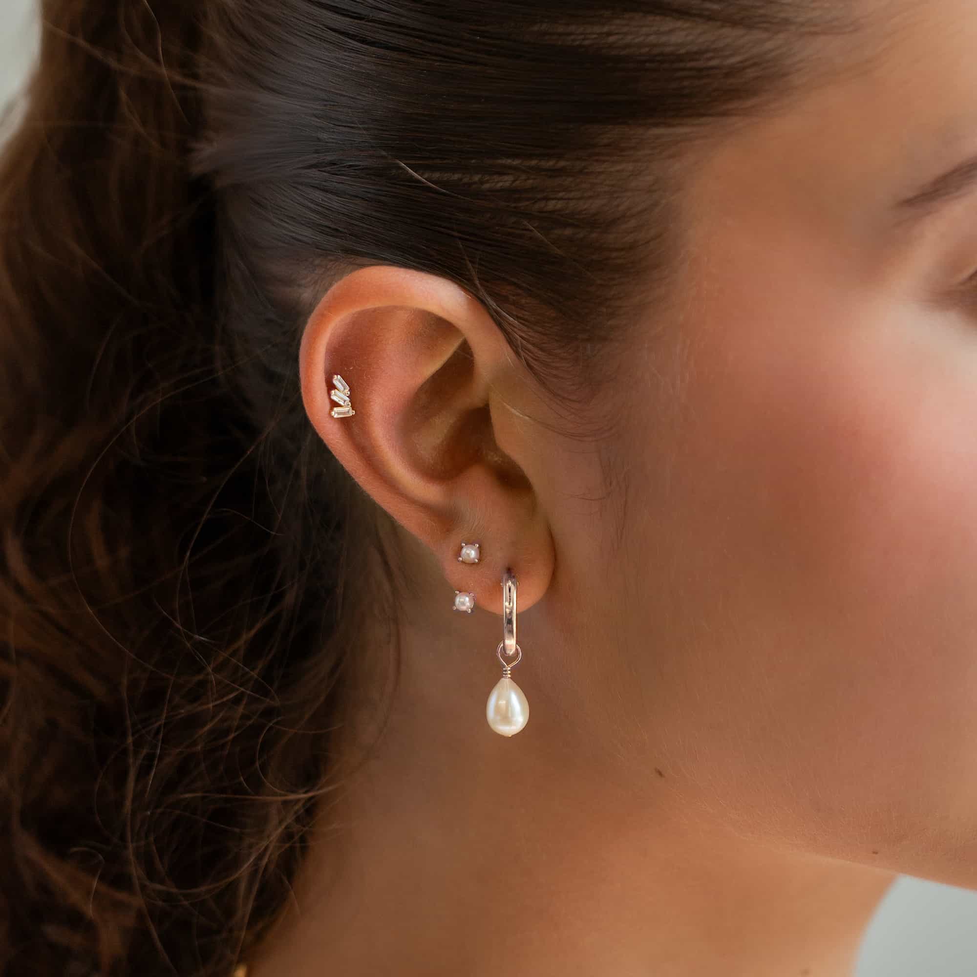 Sterling silver three-baguette flat back stud shown in a helix piercing on a model's ear