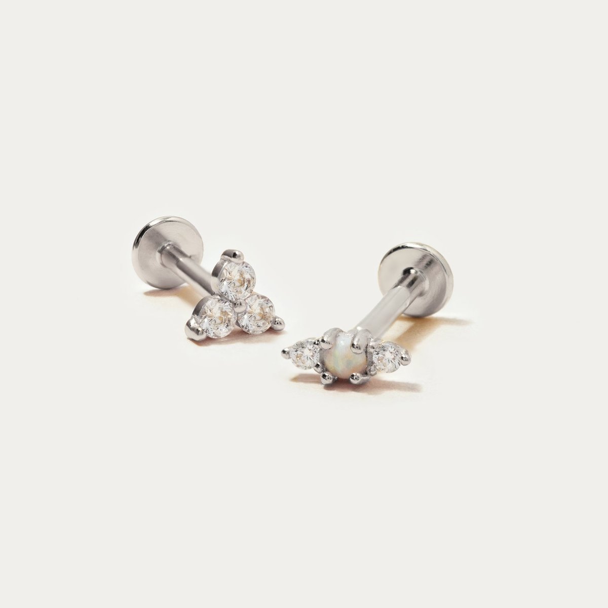 Sterling silver trio flat back studs with a white opal and clear stones, shown on a cream background