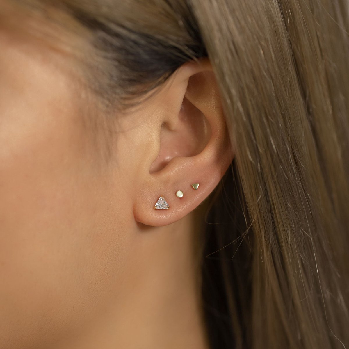 14K gold trillion white zirconia stud with smaller studs, shown on a model's ear