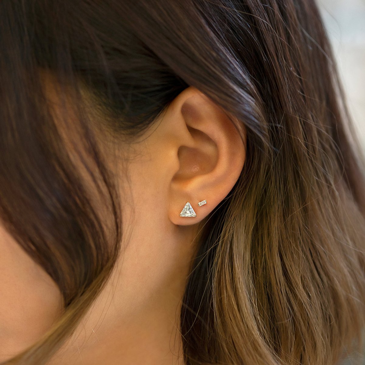 Gold vermeil crystal baguette flatback stud shown on a model's lobe beside a triangle stud