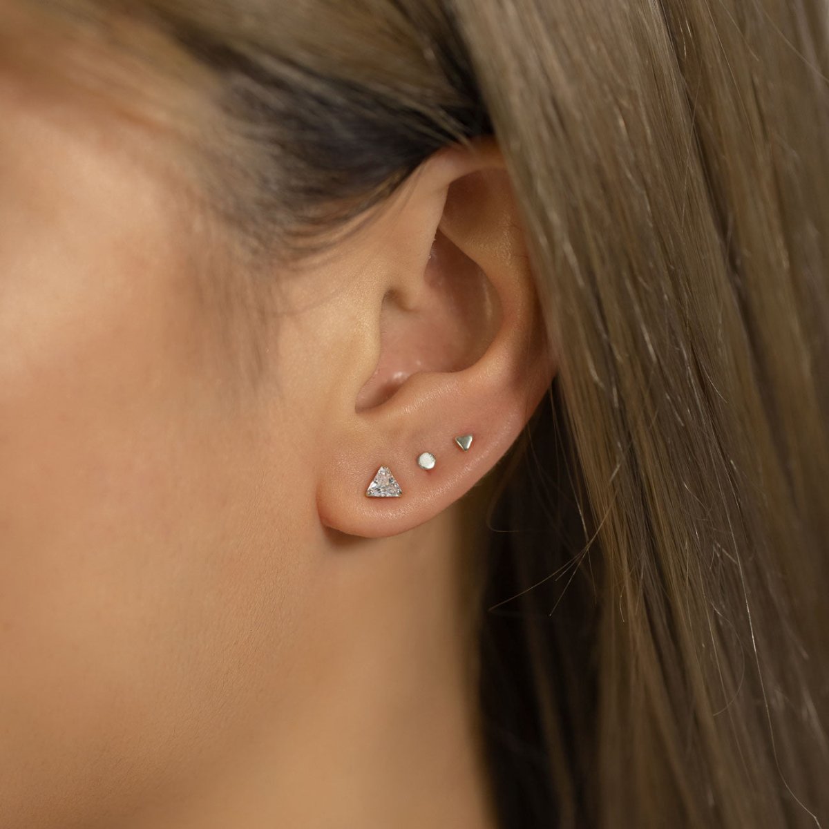 14K white gold trillion white zirconia stud with tiny studs, shown on a model's ear