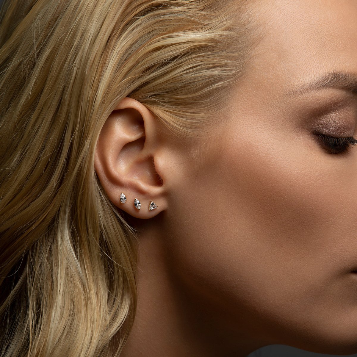 14K white gold white zirconia studs stacked along the lobe, shown on a model's ear