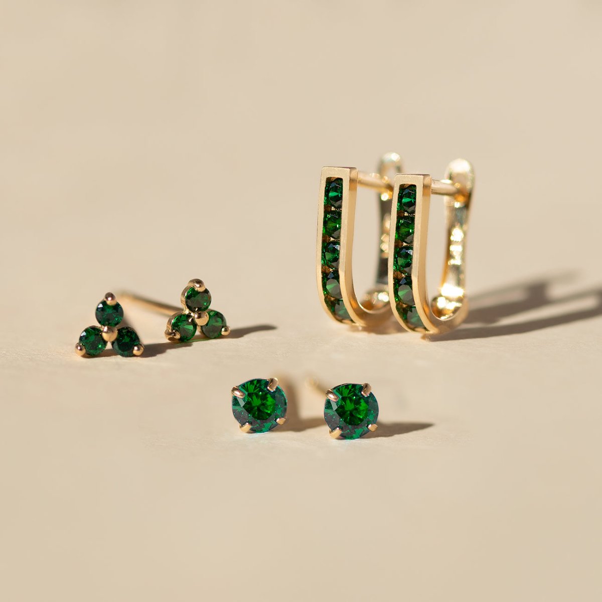 Close up of earring featuring 14K Gold Gemstone Emerald  CZ Crystal stud and hoop collection 
