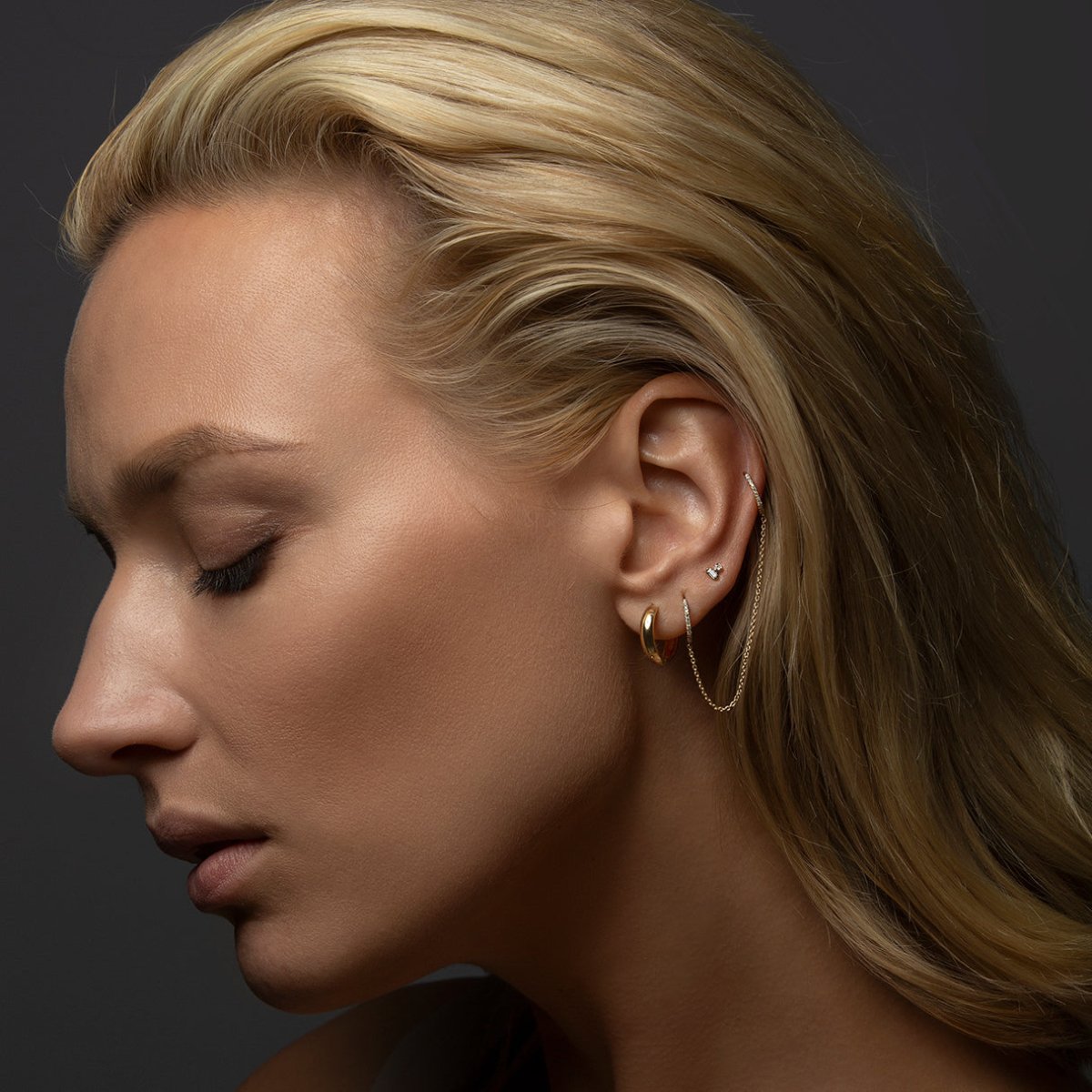 14K rose gold baguette and round diamond duet studs shown on a model's upper lobe