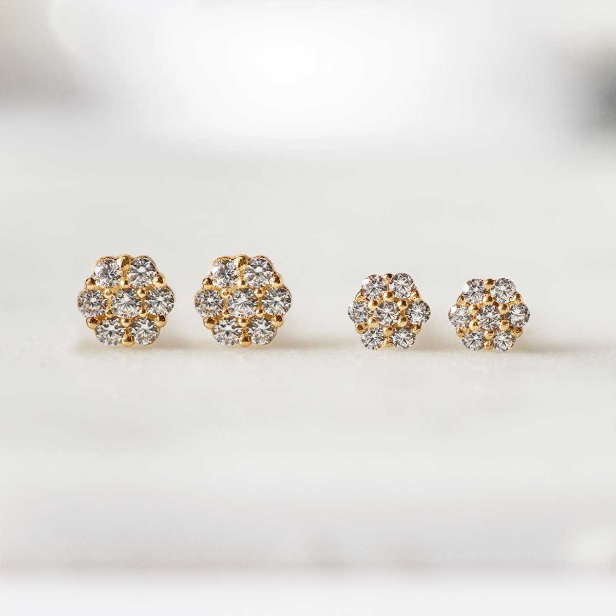 Two pairs of 14K gold pavé disc studs in different sizes, size comparison on a cream background