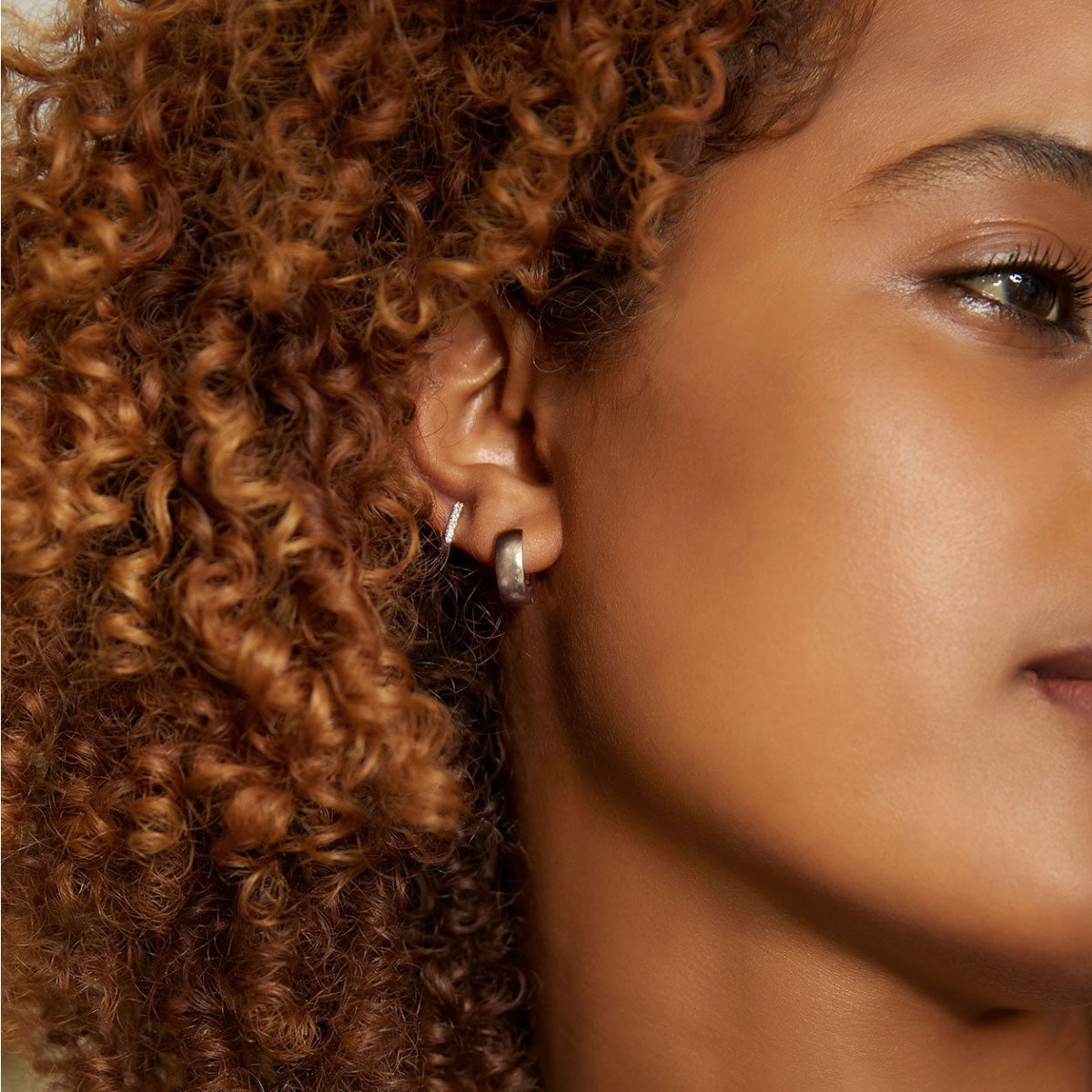 14K white gold pavé diamond huggie hoop, shown on a model's lobe