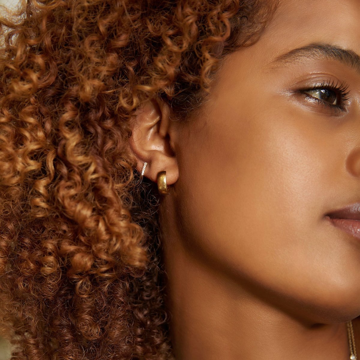 14K gold pavé diamond huggie hoops, shown on a model's lobe