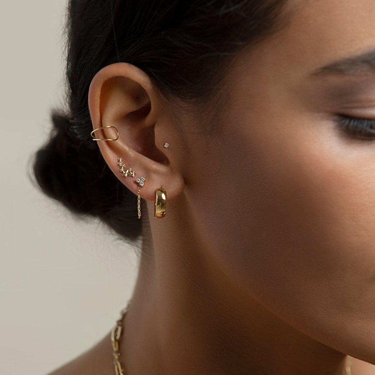 14K gold star cluster stud styled in an ear stack with a gold hoop, on a model