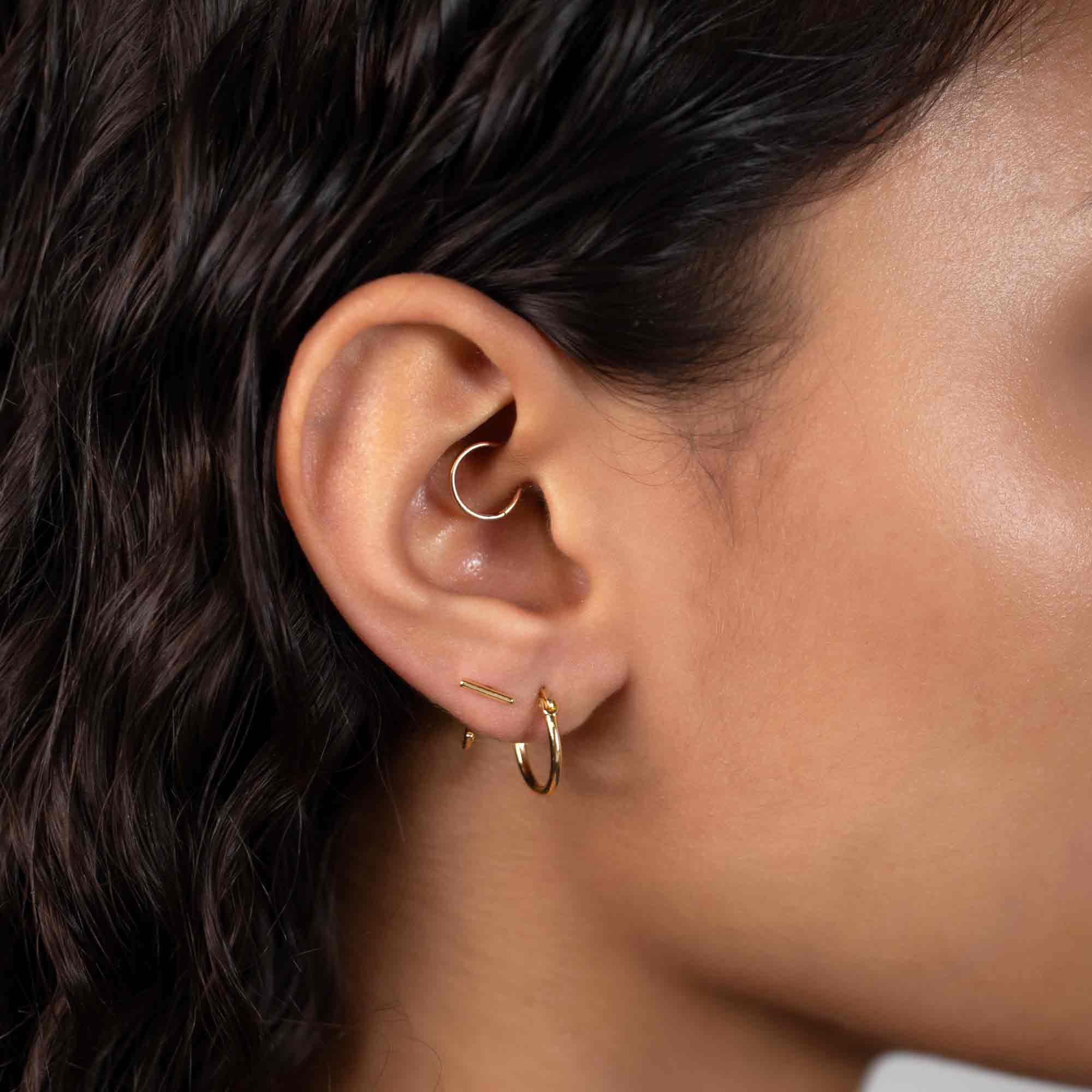 Gold vermeil bar huggie earrings styled in a multi-piercing ear stack on a model