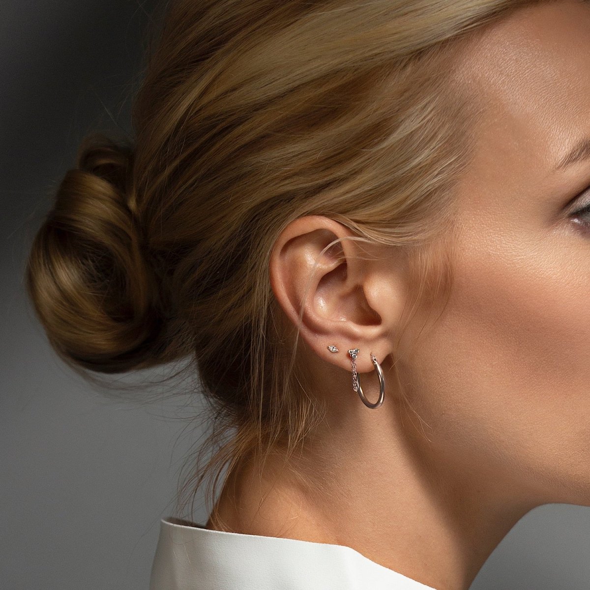 14K white gold diamond chain stud earring with a draped chain, shown on a model's ear with a hoop