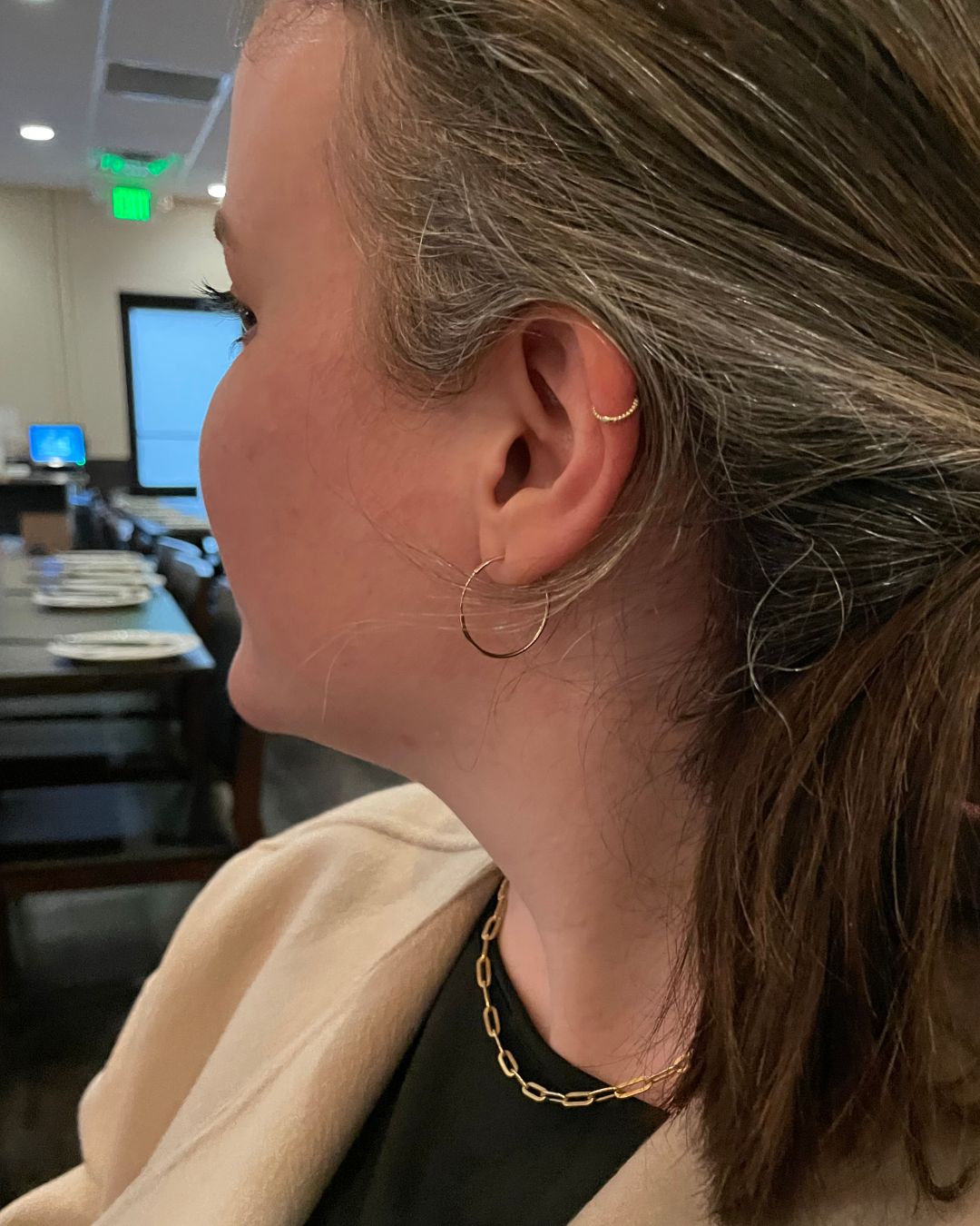 Side view of a worn ear with a thin gold lobe hoop, a beaded gold ear cuff, and a gold link chain necklace