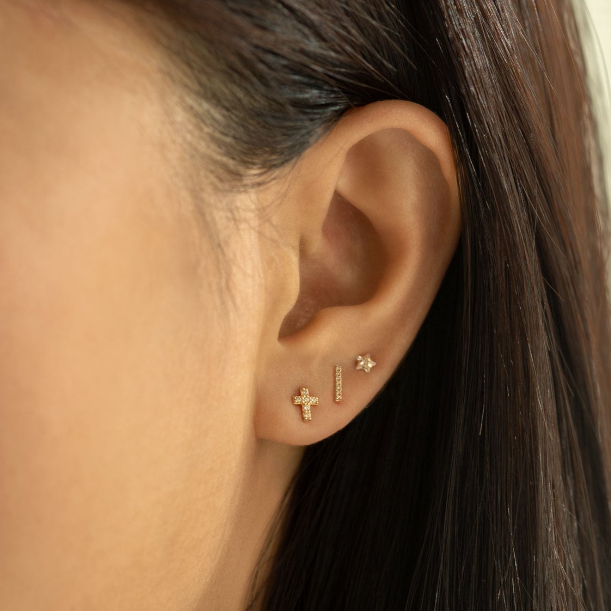 Rose gold vermeil pavé zirconia cross stud shown on a model's lobe, side profile