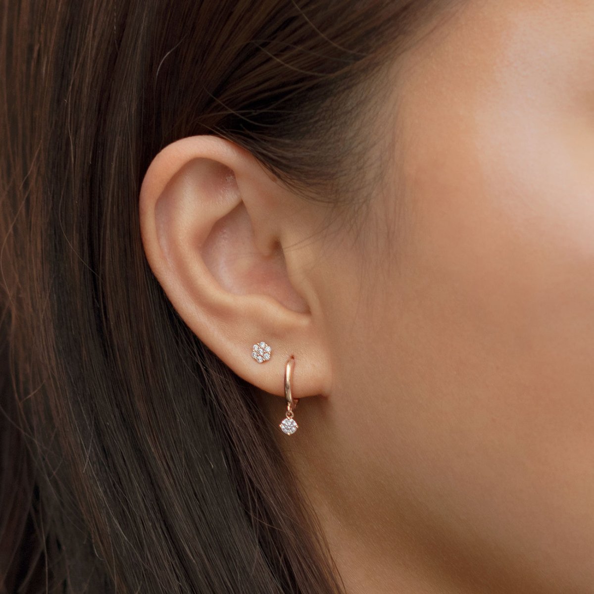 14K rose gold moissanite dangle huggie shown on a model's lobe with a pavé stud above