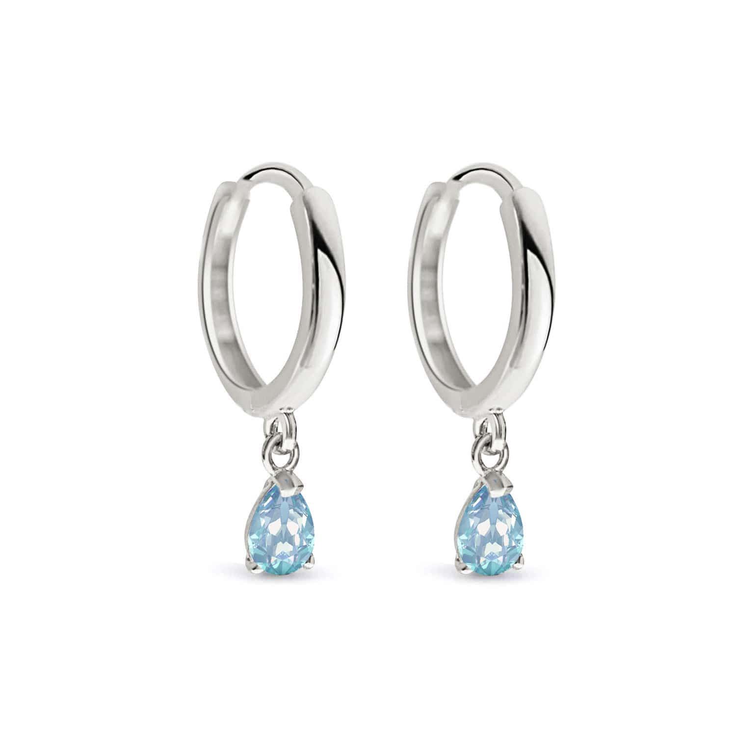 Pair of 14K white gold huggie hoops with pear-cut aquamarine drops, on a white background