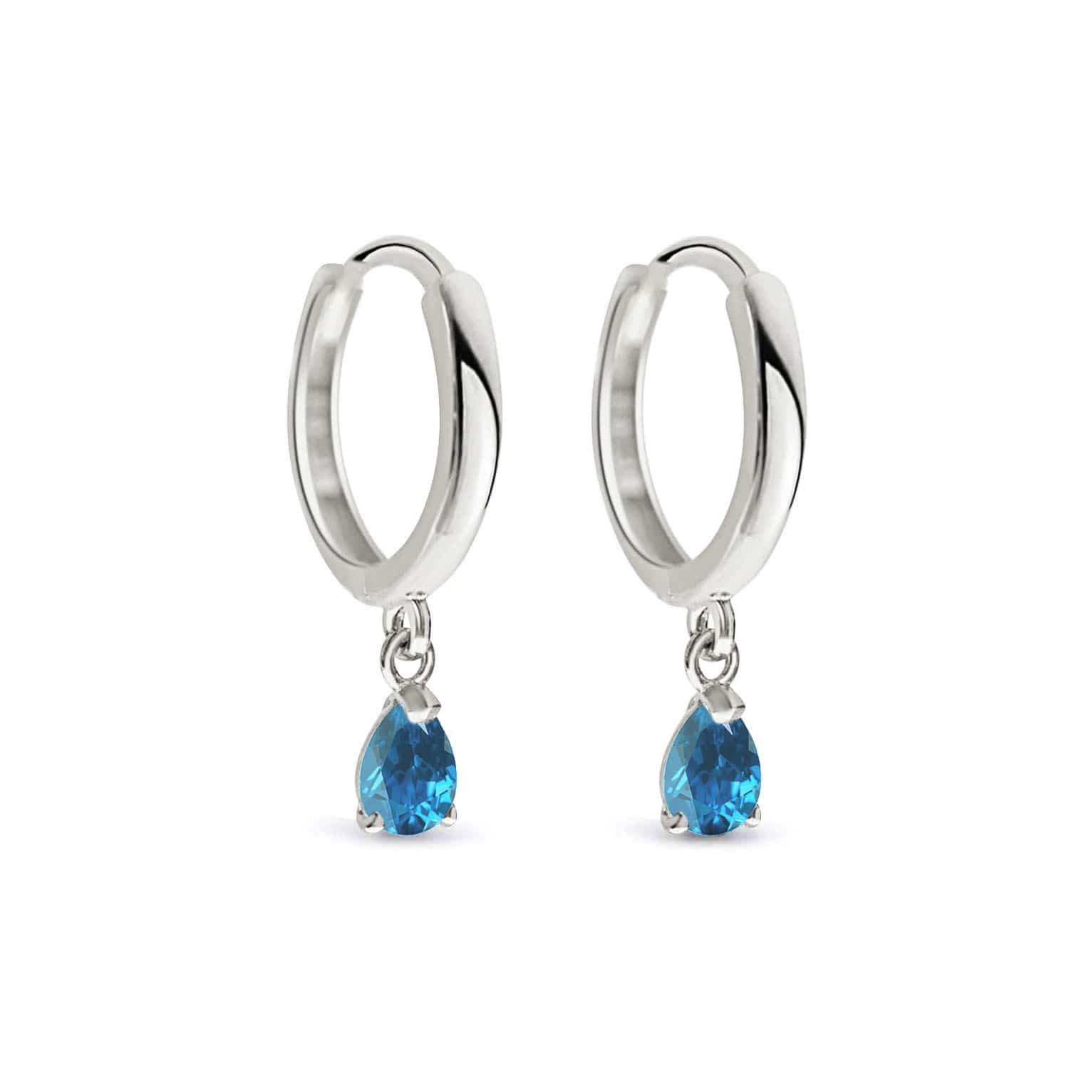 Pair of 14K gold huggie hoops with pear-cut blue zircon drops, on a white background