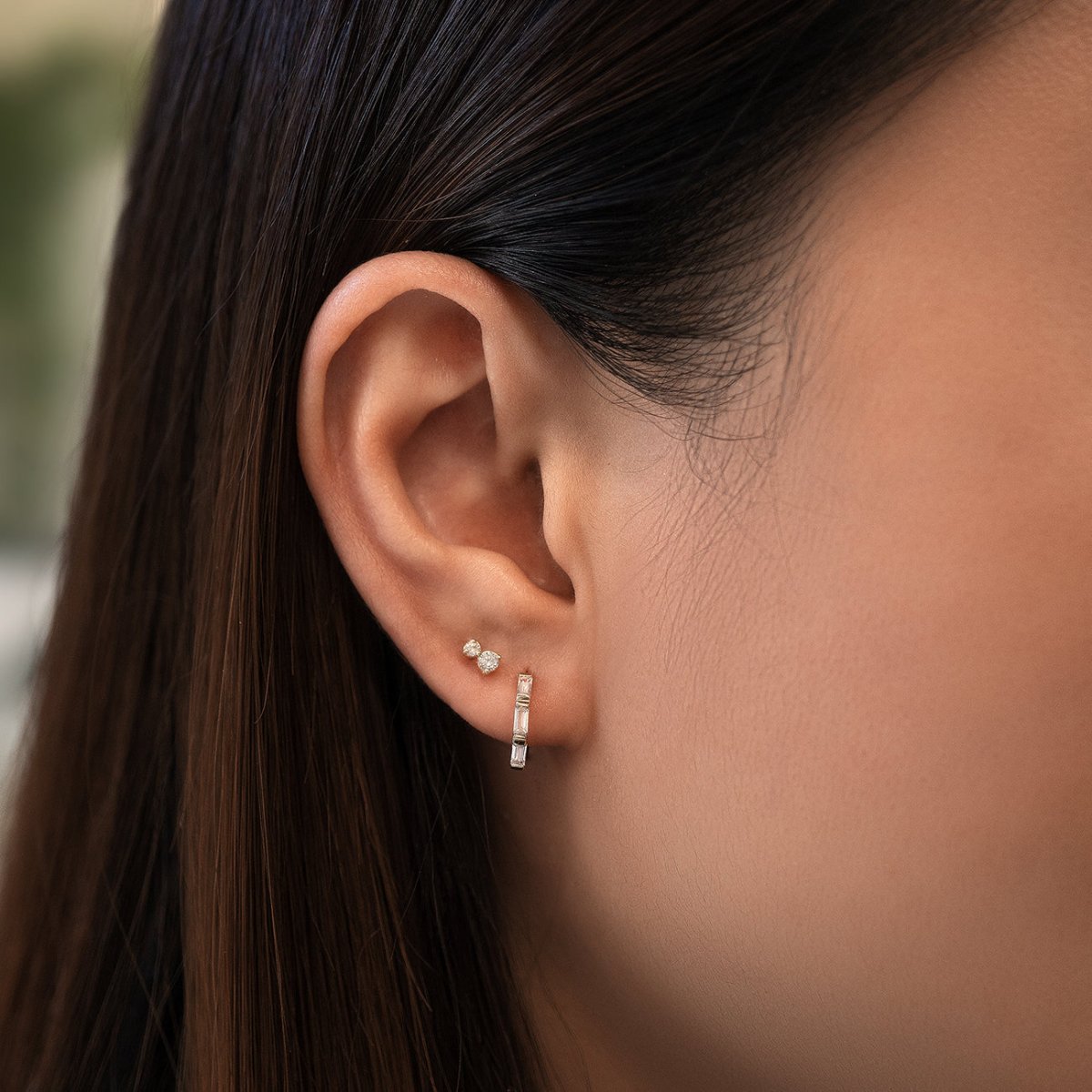 Sterling silver baguette huggie hoop with clear stones, shown on a model's lobe