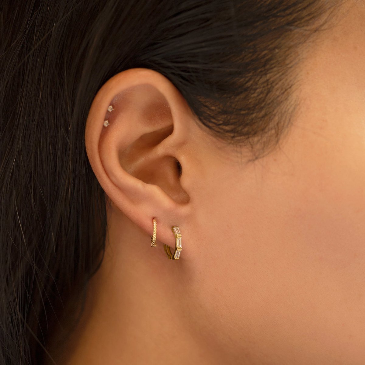 Gold vermeil baguette huggie hoop with clear stones, shown on a model's lobe