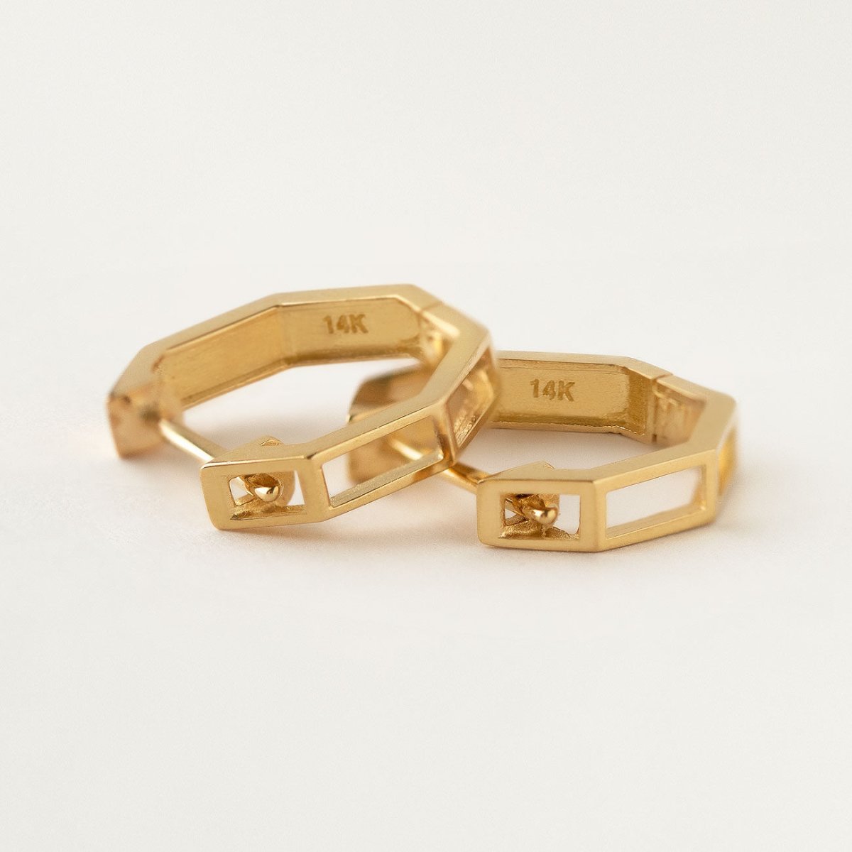 14K gold octagon huggie hoops, close-up detail showing the 14K stamp and open design on a cream background