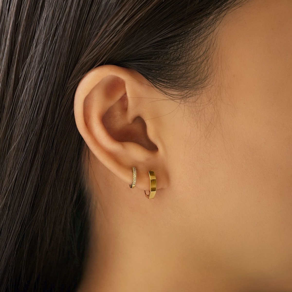 14K gold pavé diamond huggie shown on a model's lobe beside a plain gold hoop