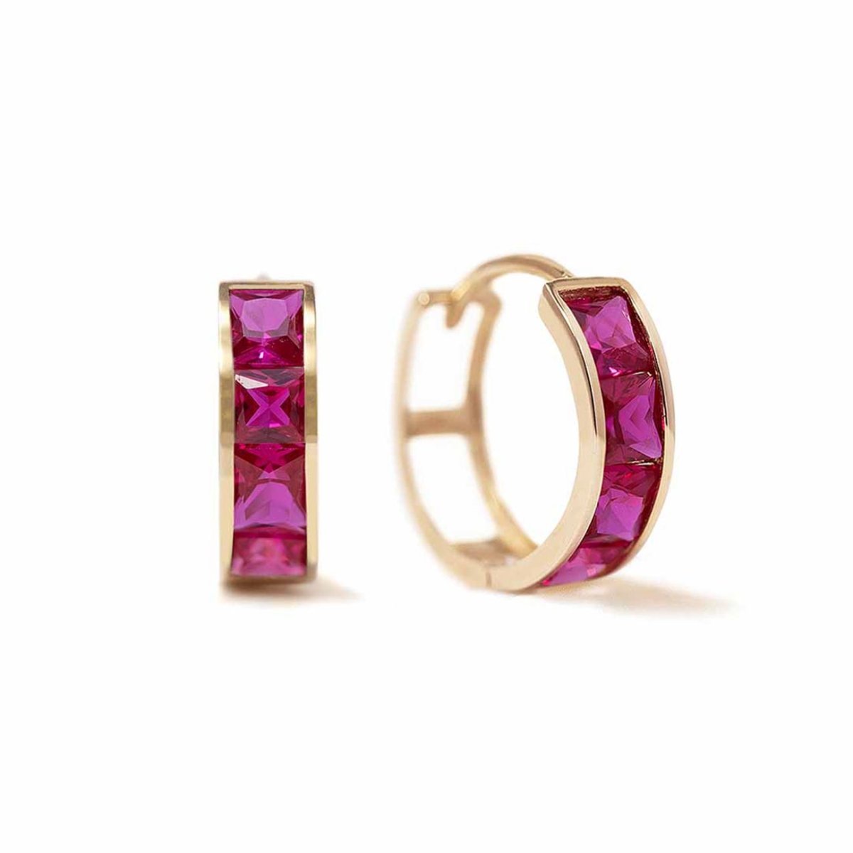 Pair of 14K gold huggie hoops with square red ruby stones, on a white background