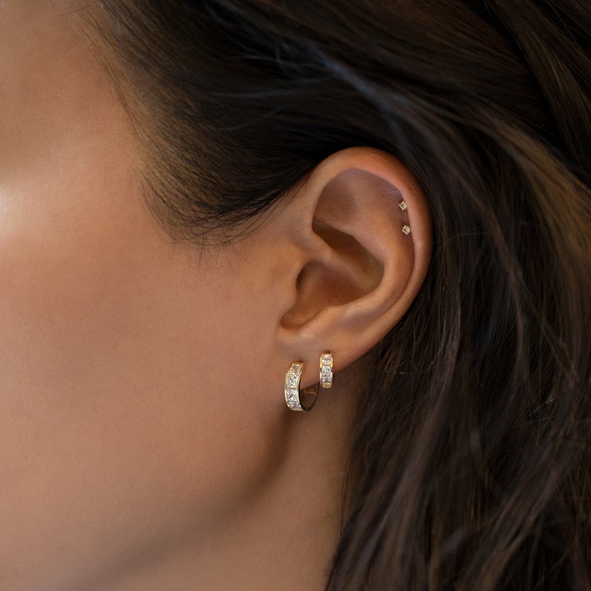 Gold vermeil flat back stud with clear zirconia stones, shown as huggie hoops on a model's lobe