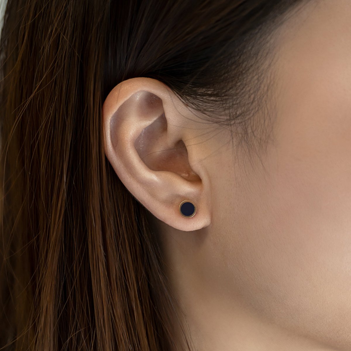 14K gold round onyx stud earring shown on a model's lobe, close-up