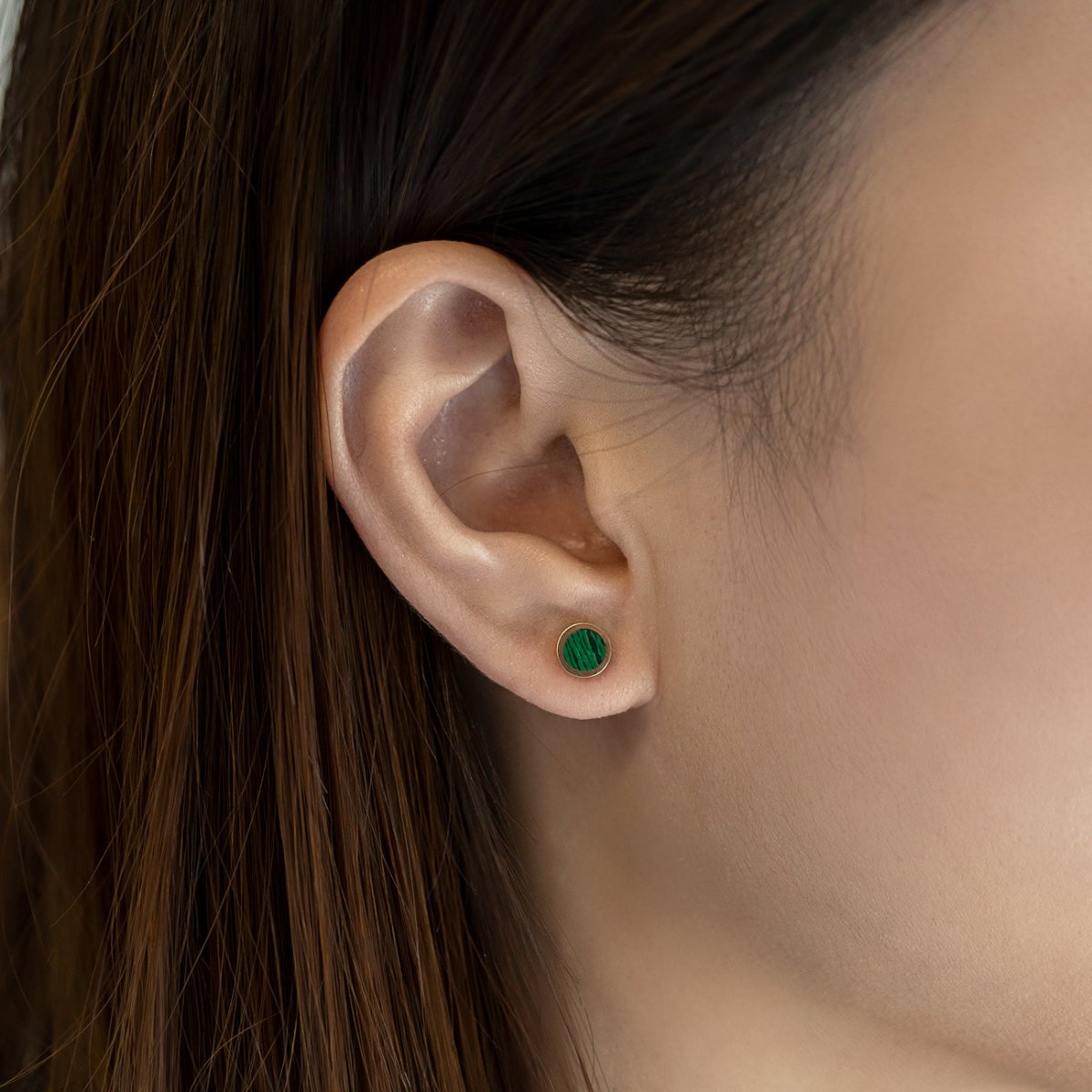 14K gold round stud with a green striped malachite stone, shown on a model's lobe