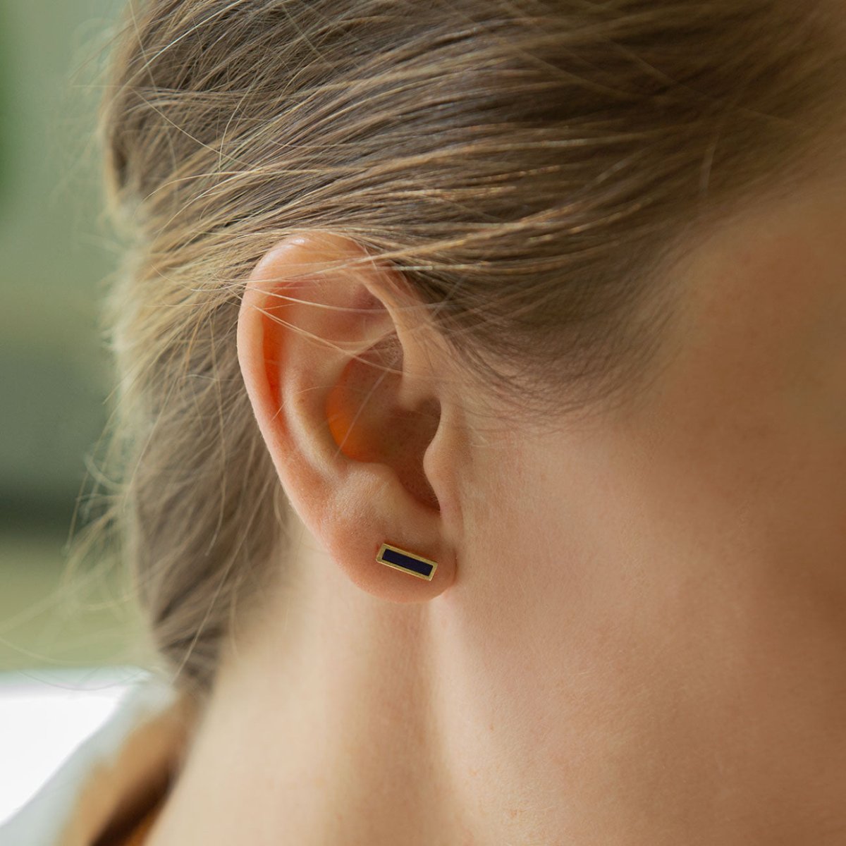14K gold lapis lazuli bar stud with a blue rectangular stone, shown on a model's lobe