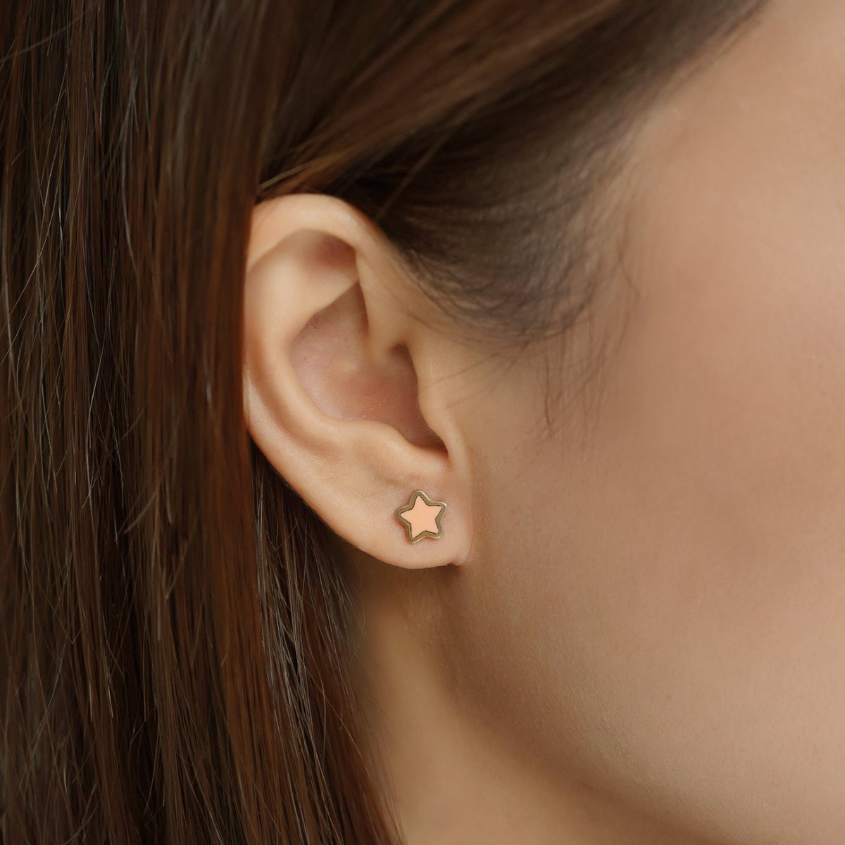 14K gold star studs in white, green and pink stone variants arranged on a cream surface