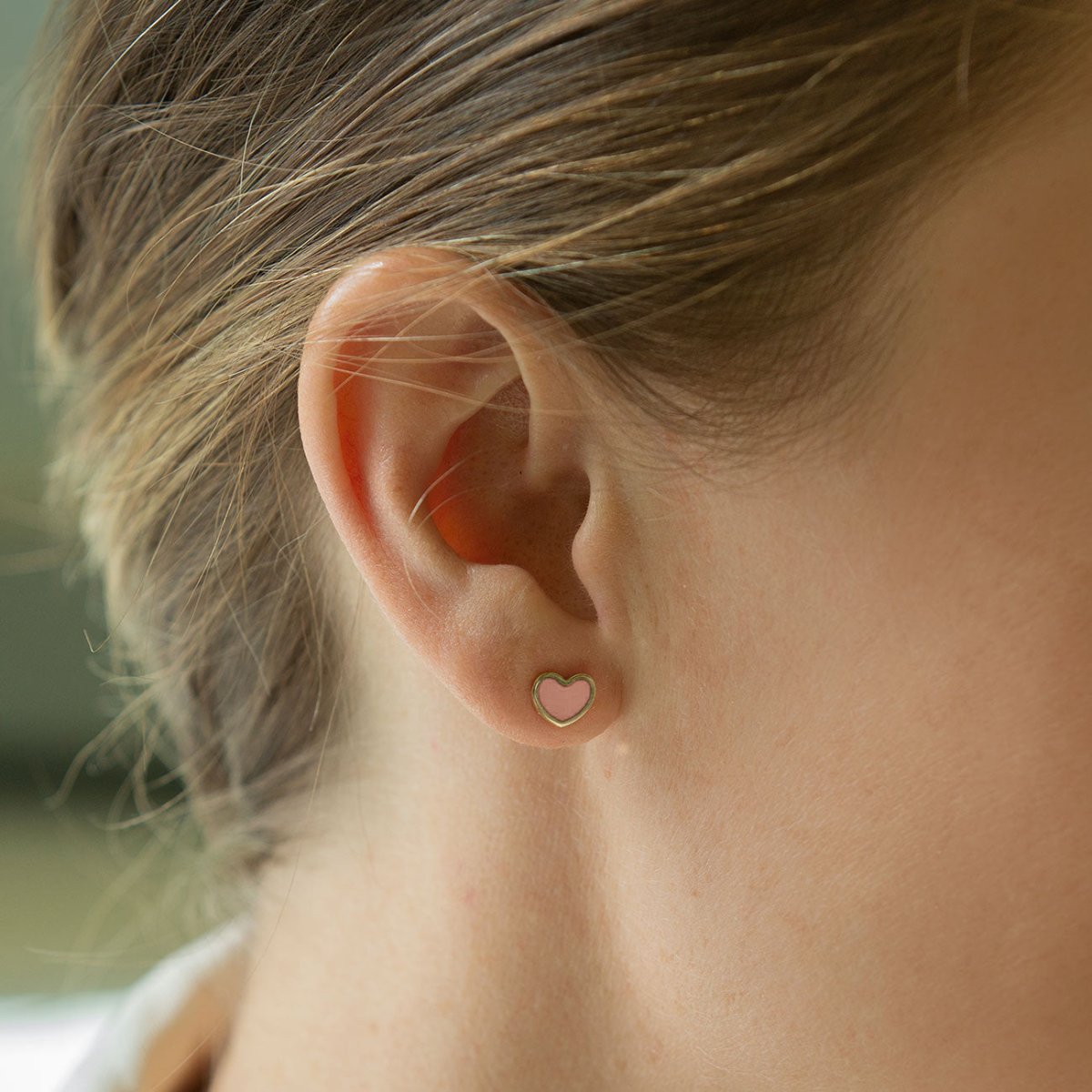 14K gold rose quartz heart stud, shown close on a model's lobe