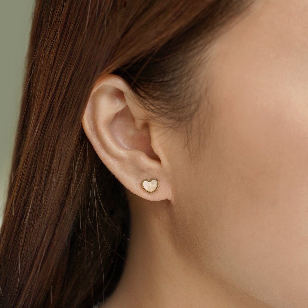 14K gold heart stud with a mother of pearl center, shown on a model's lobe