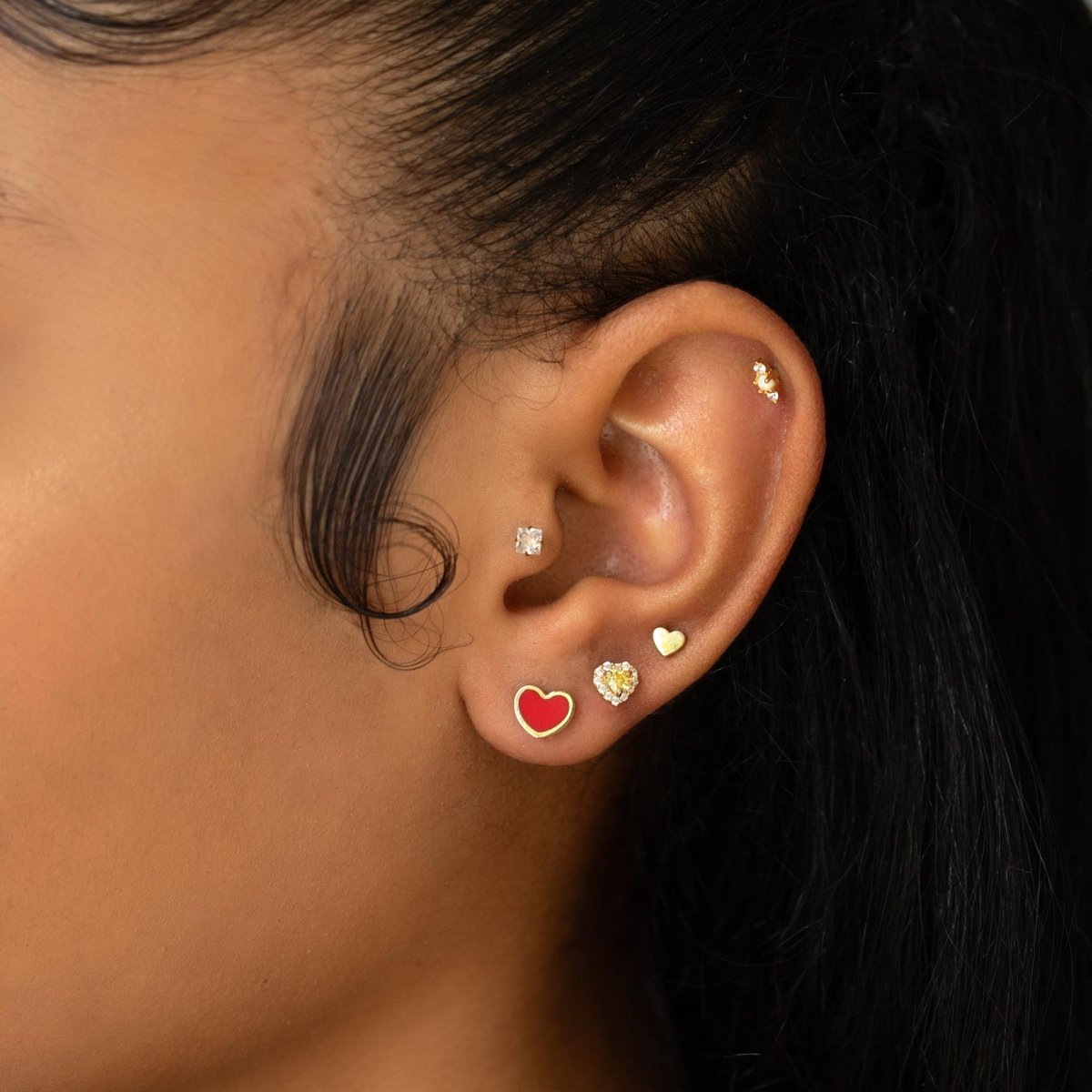 14K gold heart stud with red carnelian inlay, shown on a model's earlobe