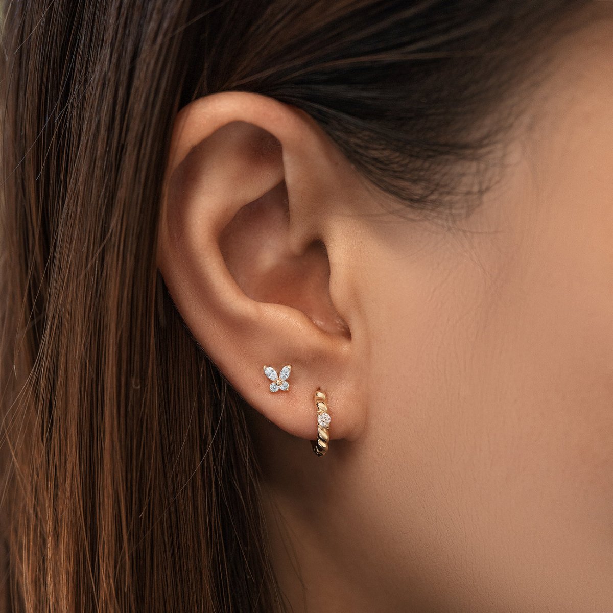 14K gold aquamarine butterfly stud with pale blue stones, shown on a model's lobe