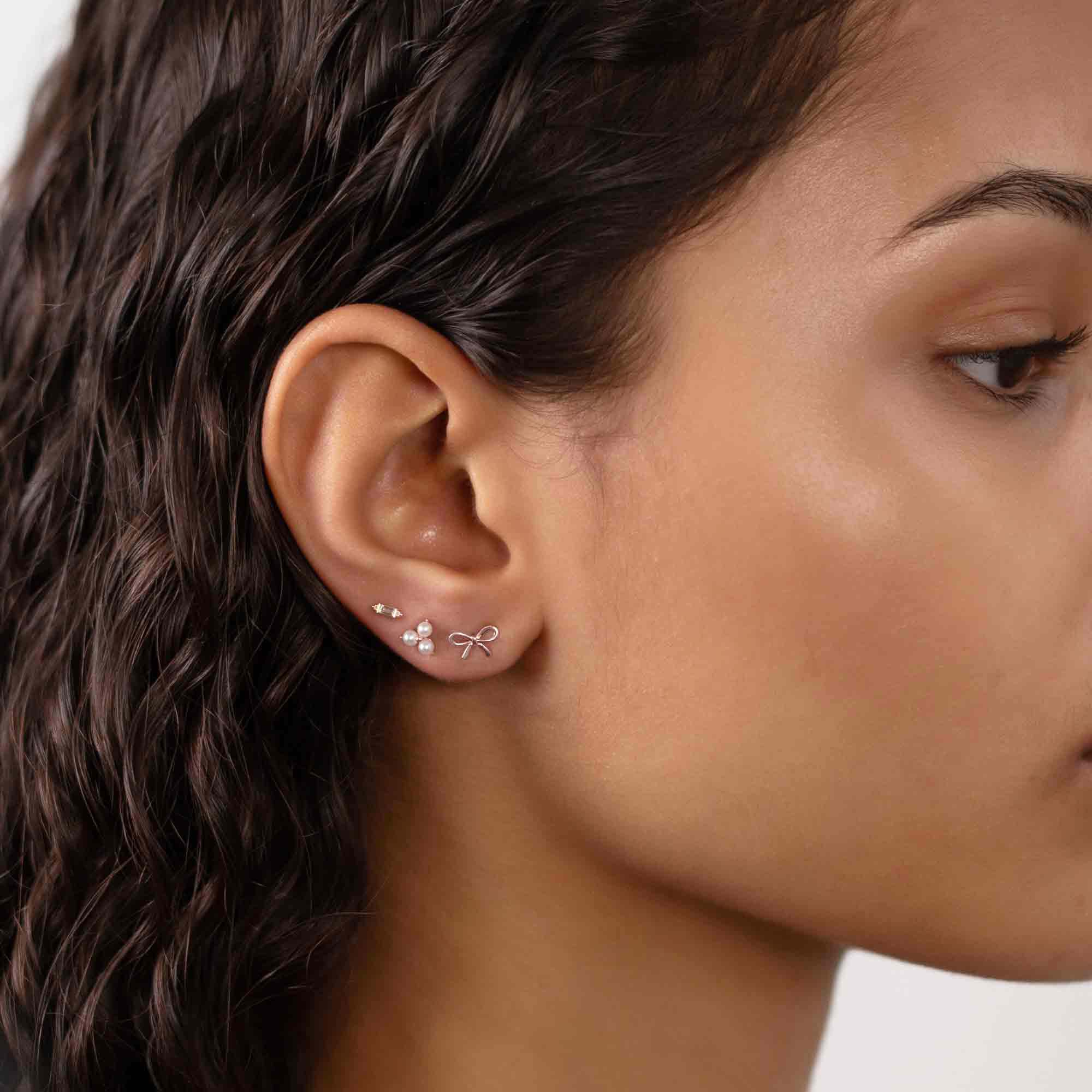 14K white gold pearl cluster studs in a curated ear stack, shown on a model's lobe