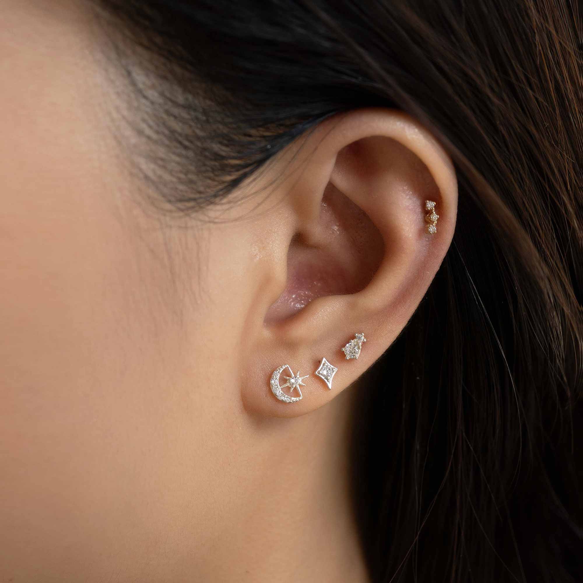 14K gold studs with clear stones in moon, star and kite shapes styled in an ear stack