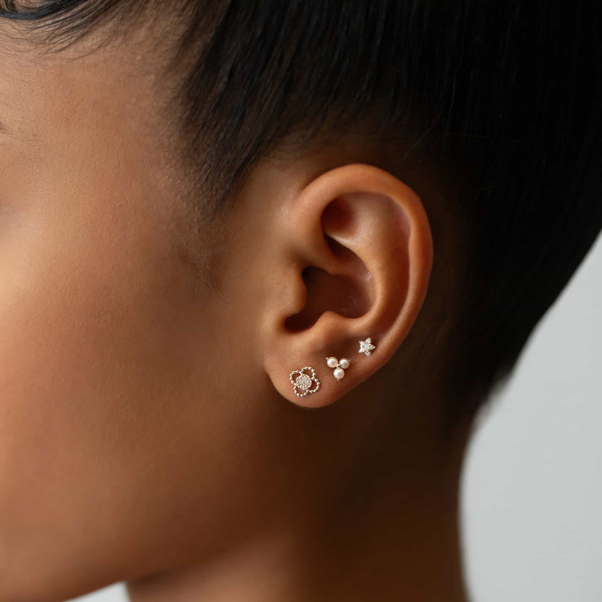 14K white gold clover stud with a beaded outline and pave white zirconia center, shown on a model's lobe