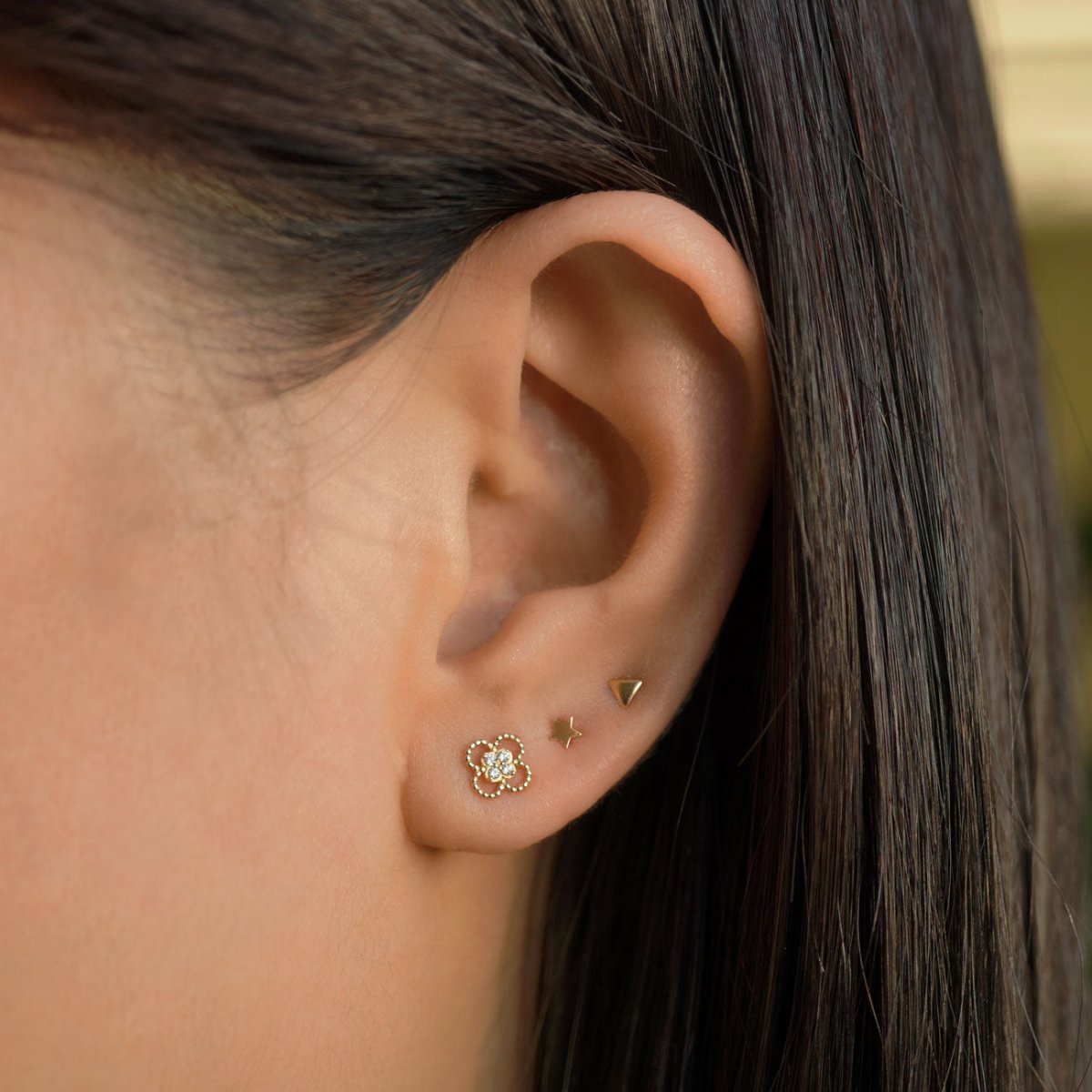 14K gold tiny star stud styled with flower, star and triangle studs on a model