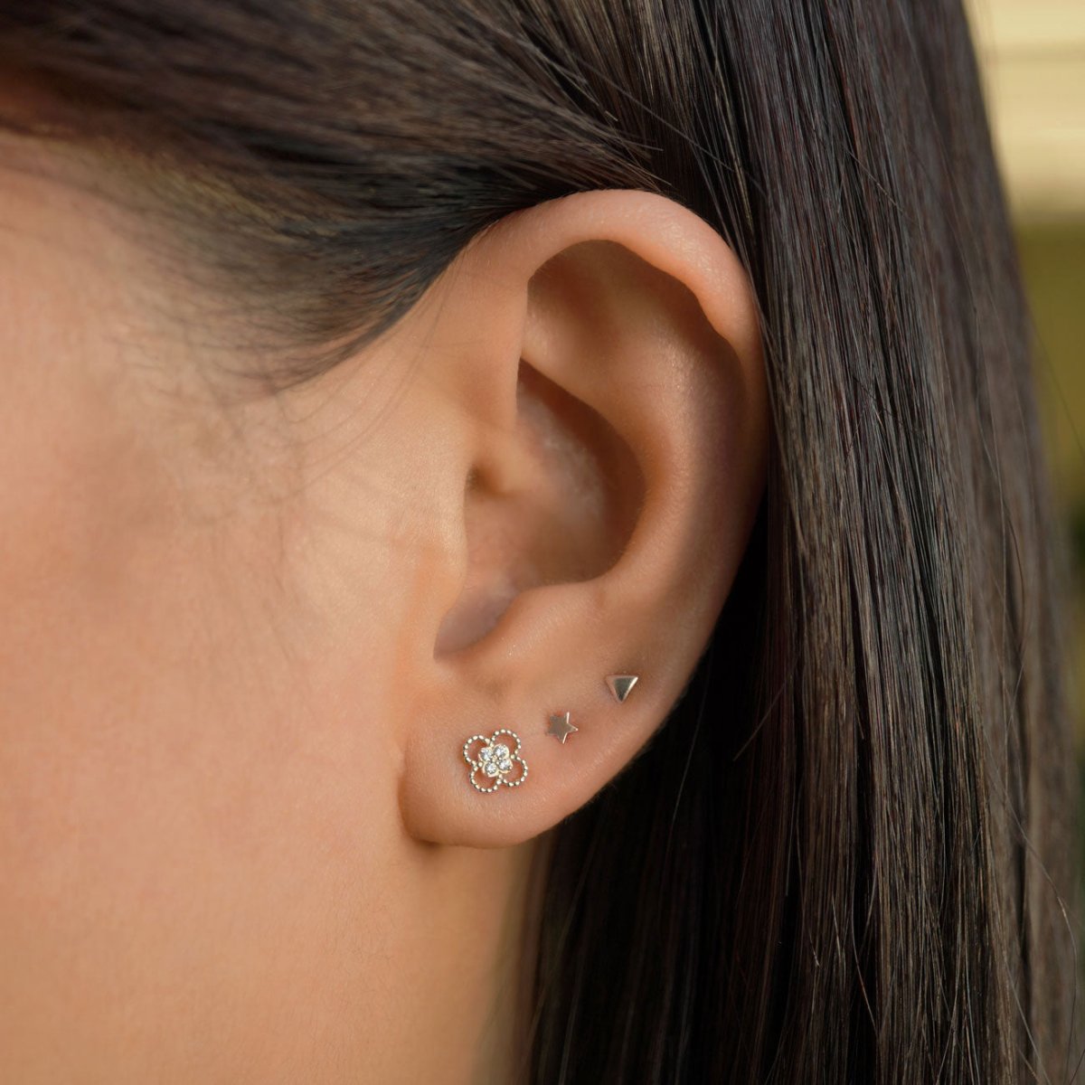 14K white gold tiny star stud shown on a model's ear, third in a silver lobe stud stack